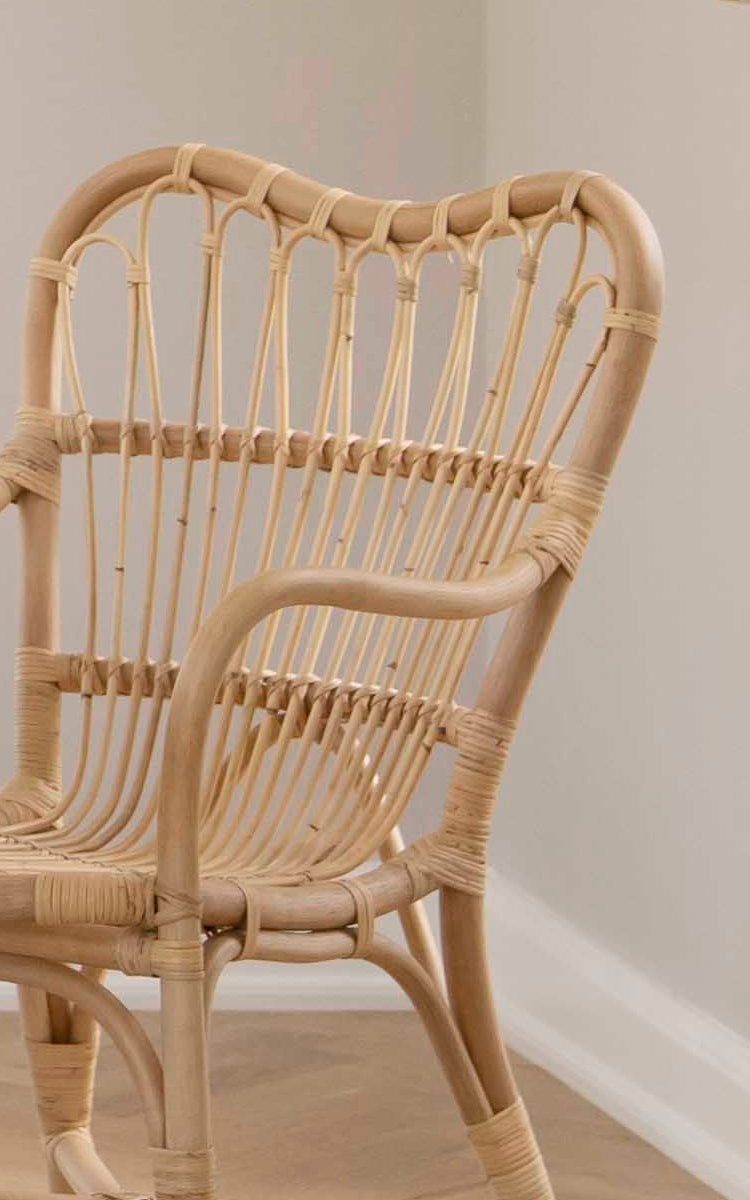 This is a close-up image of Margret Dining Chair in natural rattan. The handwoven open weave backrest and curved frame highlight the craftsmanship.
