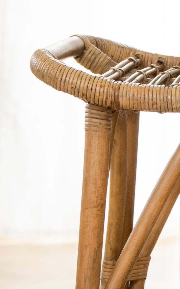 This is a close-up image of Salsa Bar Stool in antique rattan. Detail of the tripod rattan base and wrapped round seat edge.