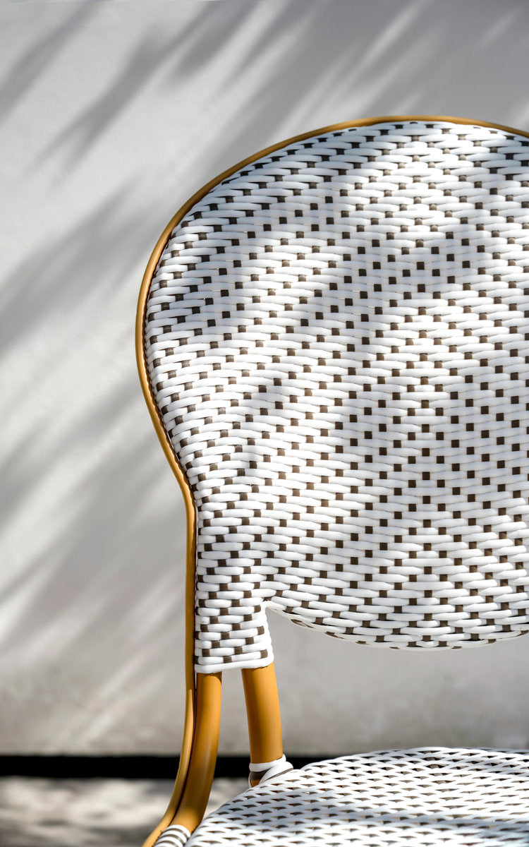 This is a close-up image of Isabell Exterior Dining Chair in almond aluminium frame white w cappuccino dot artfibre. Woven oval backrest in sunlight.