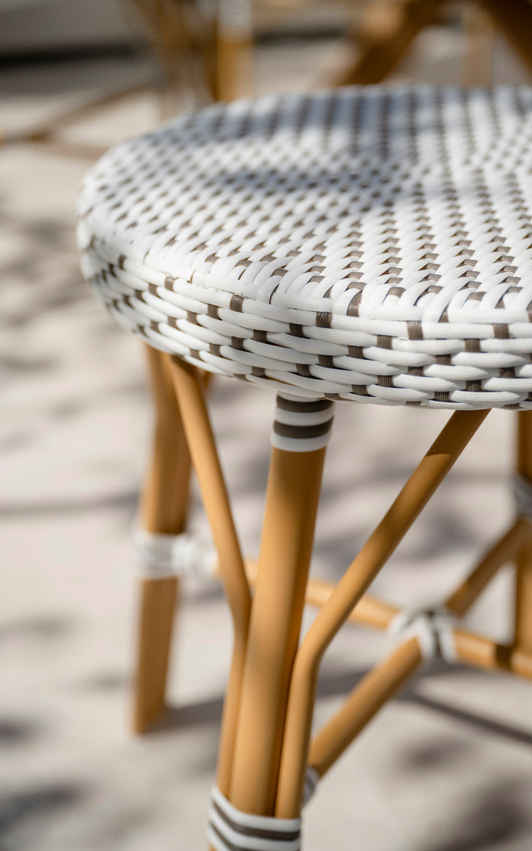 This is a close-up image of Simone Exterior Stool in almond aluminium frame white w cappuccino dot artfibre. Woven seat and wrapped legs in sunlight.