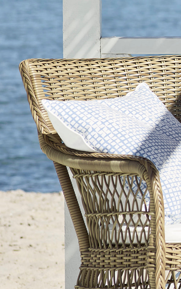 This is a close-up image of Marie Exterior Armchair in antique grey artfibre aluminium. Detail of the lattice weave and armrest.