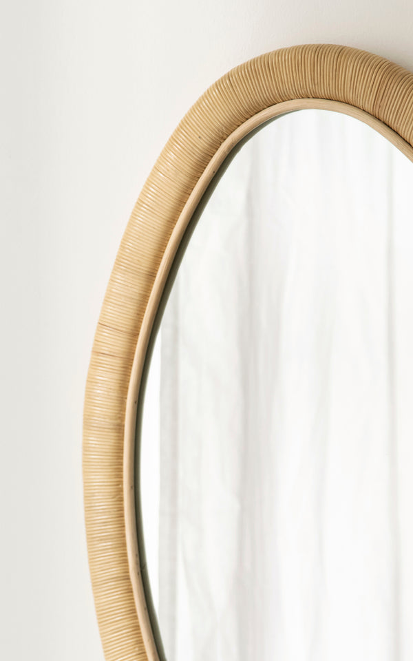 This is a close-up image of Malou Mirror in natural rattan. Wrapped rattan frame with organic oval shape and soft light.