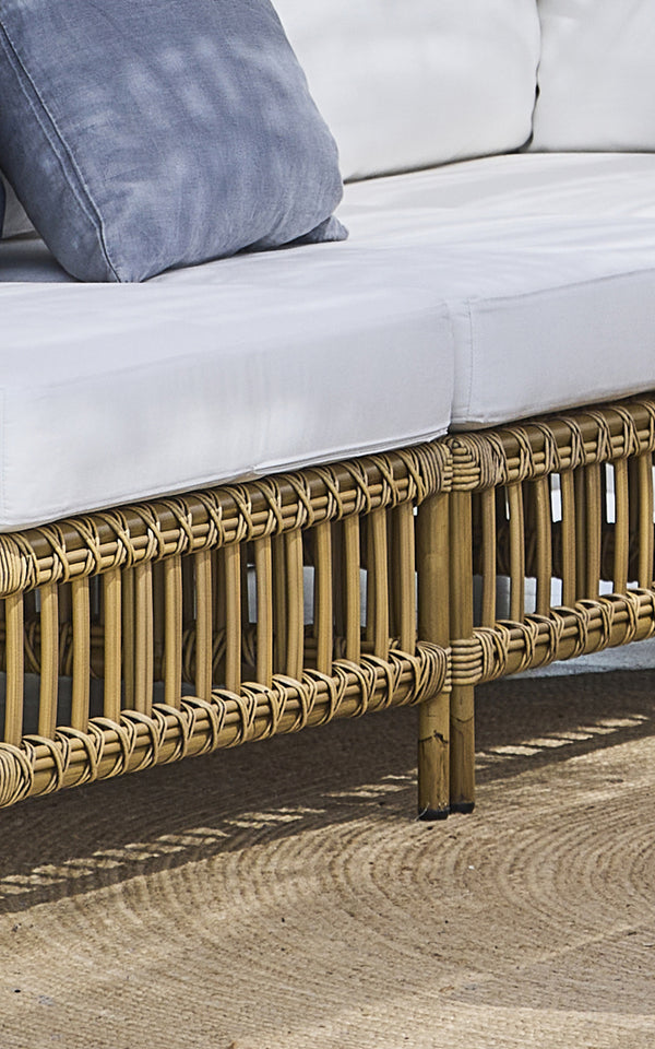 This is a close-up image of Maggie Sofa Center Module in antique aluminium artfibre. Base frame with cross-weave detail and jute rug beneath.