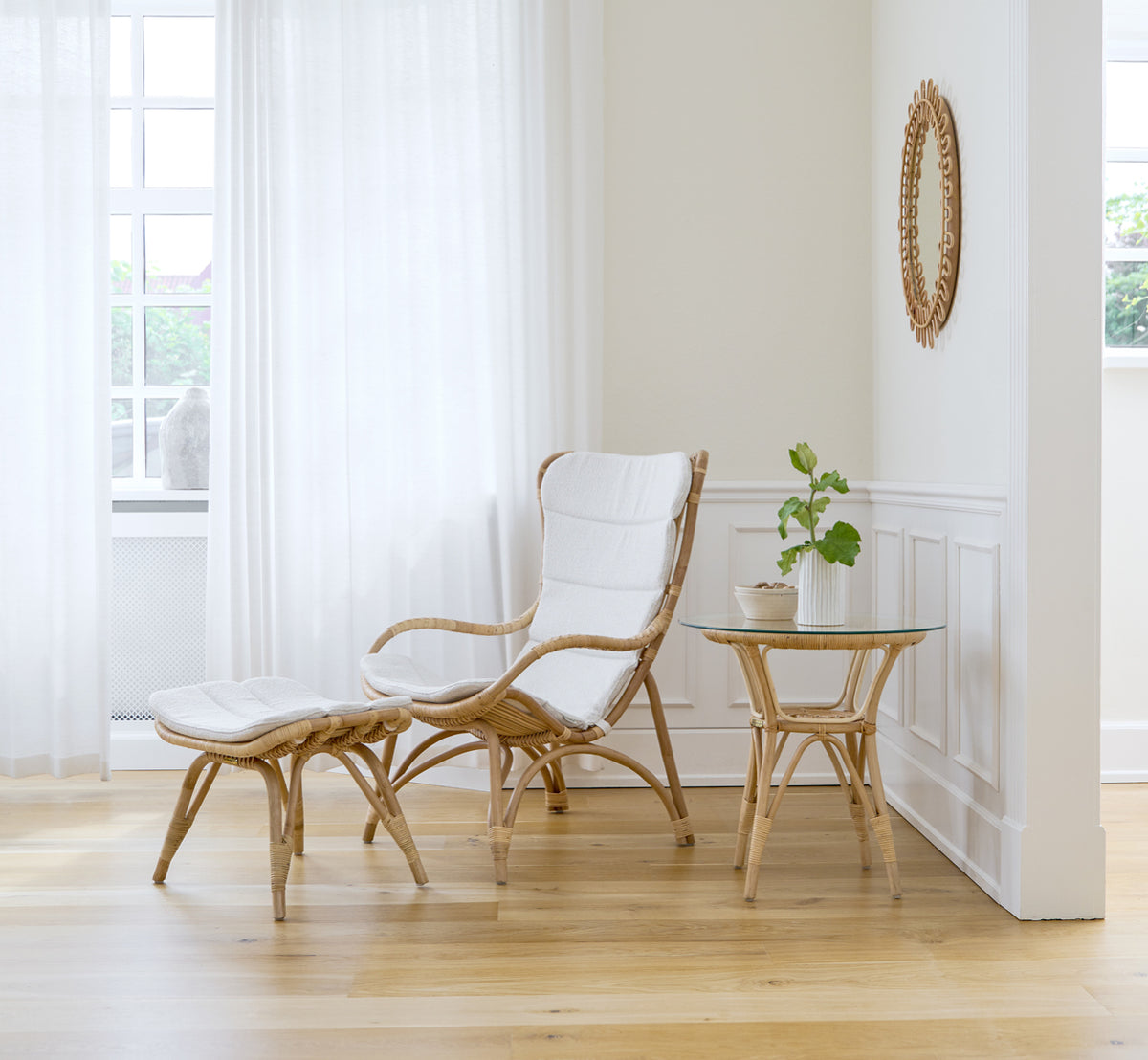 This is a lifestyle image of Monet Lounge Chair in natural rattan. In a blush-walled room with herringbone floor and rattan trolley.