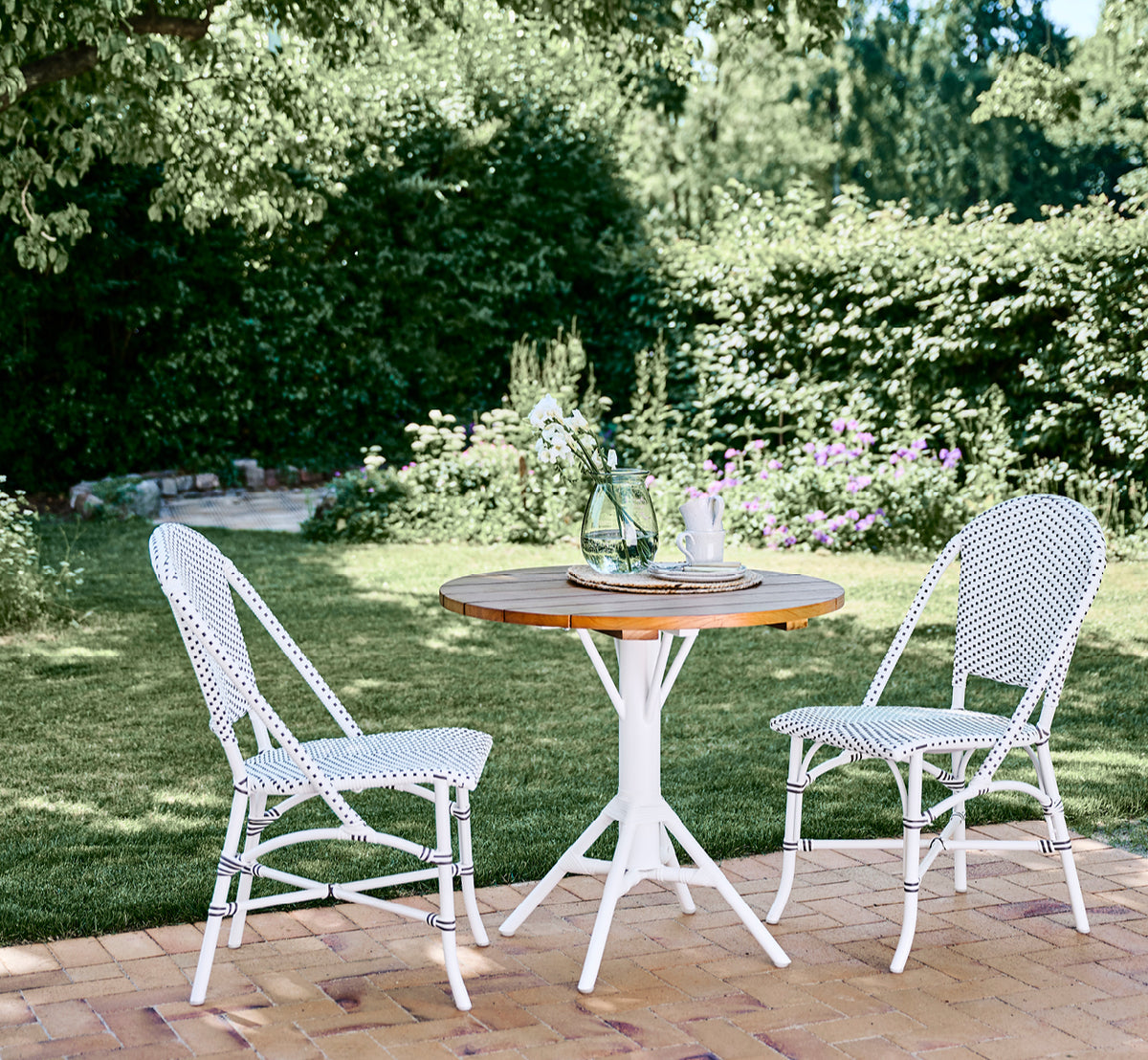 This is a lifestyle image of Sofie Exterior Dining Chair in white aluminium frame white w cappuccino dot artfibre.