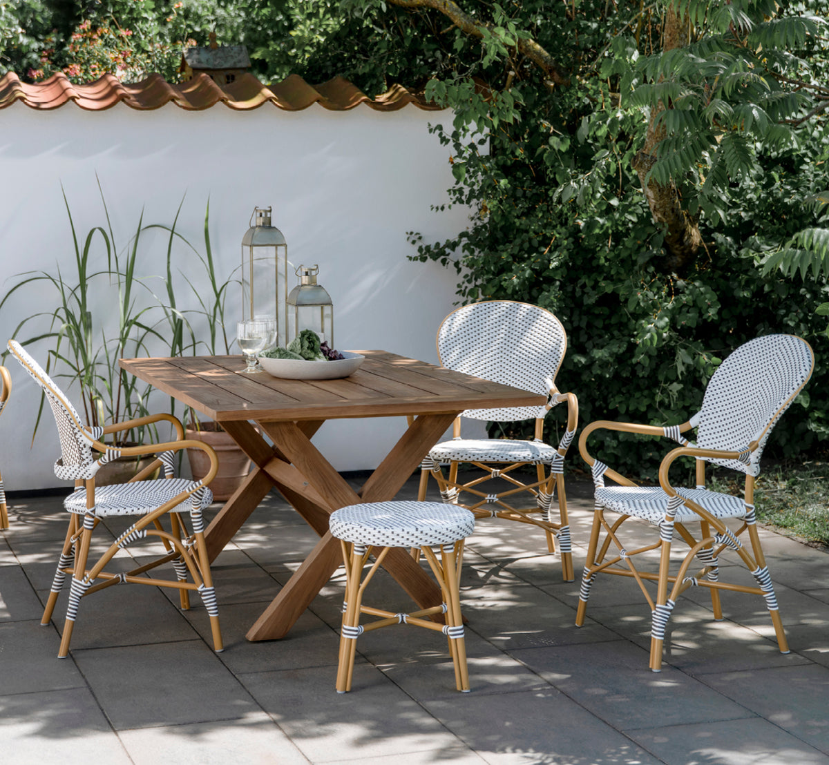 This is a lifestyle image of Isabell in almond aluminium frame White w cappuccino dot ArtFibre, in a lush garden patio with stone tile and a.