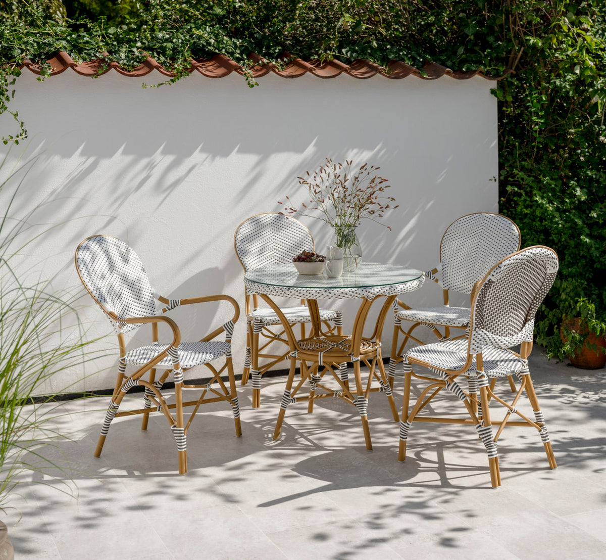 This is a lifestyle image of Isabell Exterior Dining Armchair in almond aluminium frame white w cappuccino dot artfibre. On a sunny terrace.