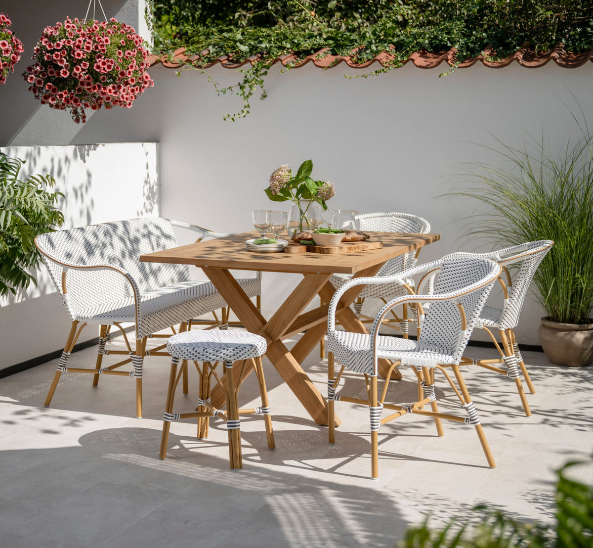 This is a lifestyle image of Simone Exterior Stool in almond aluminium frame white w cappuccino dot artfibre. With teak table on a sunny terrace.