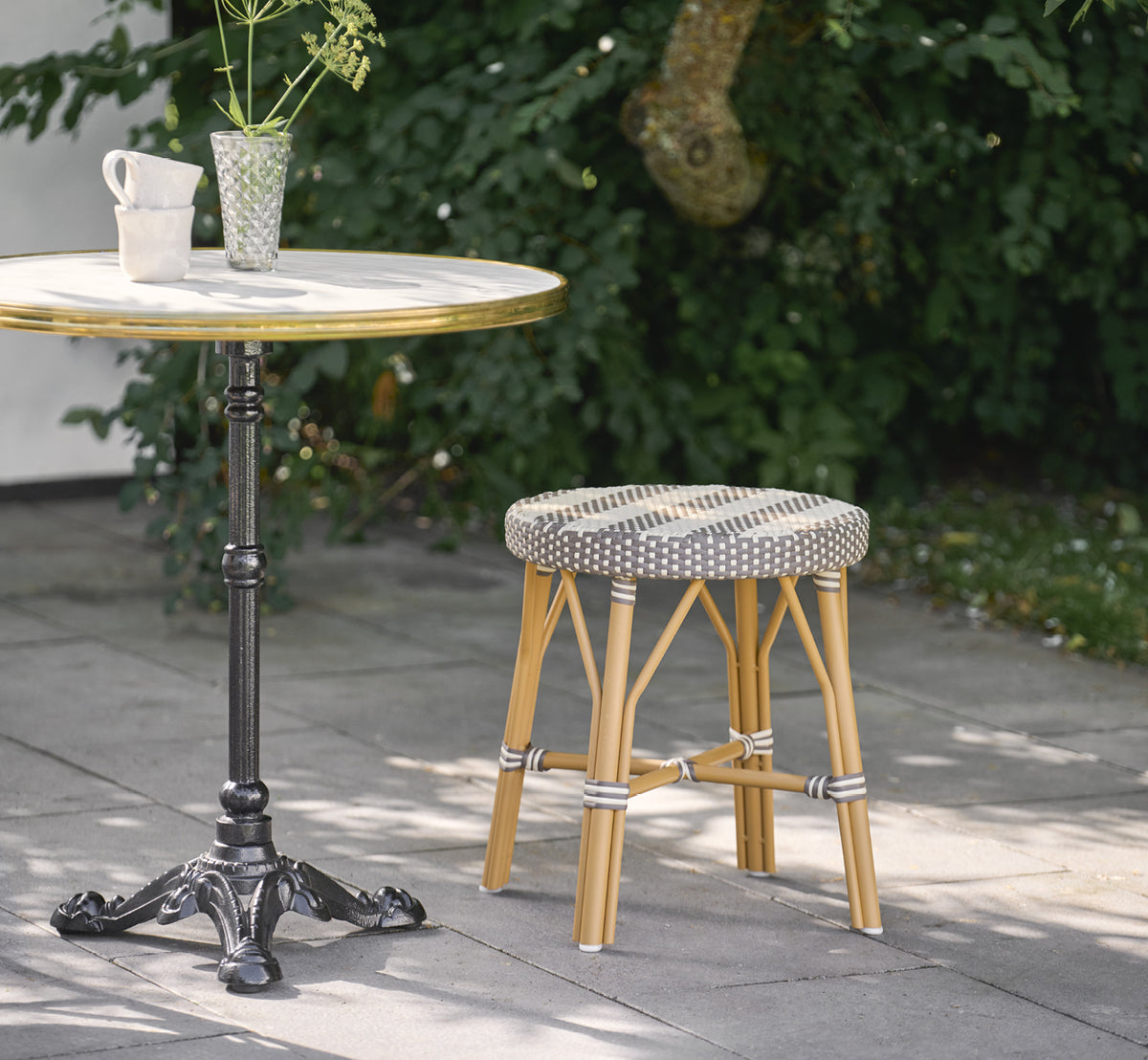This is a lifestyle image of Simone Exterior Stool in almond aluminium frame striped cappuccino ivory artfibre. Styled in a bright interior setting.
