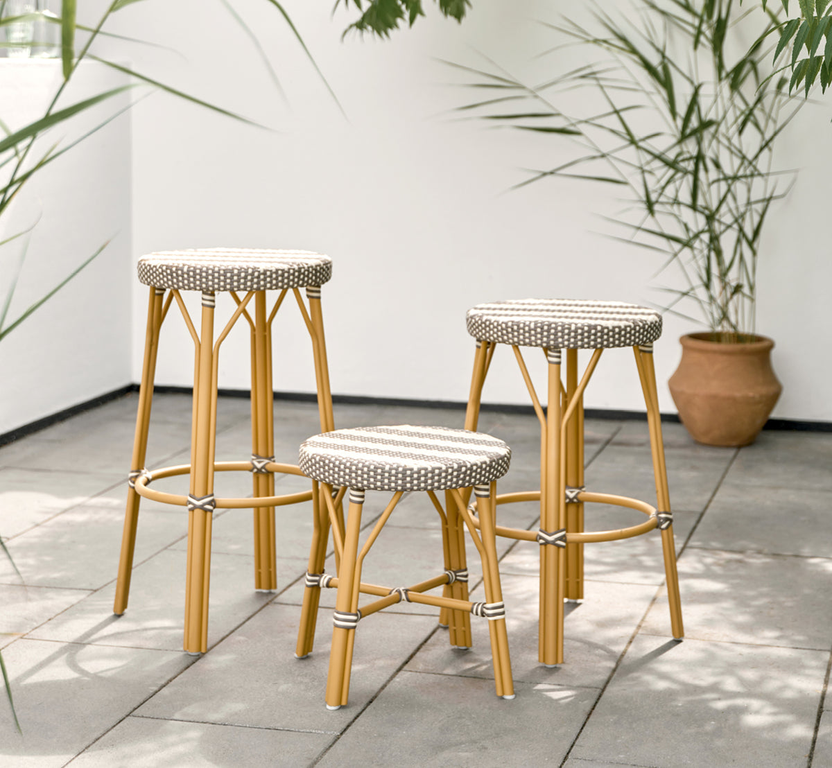 This is a lifestyle image of Simone Exterior Stool in almond aluminium frame striped cappuccino ivory artfibre. Styled in a bright interior setting.