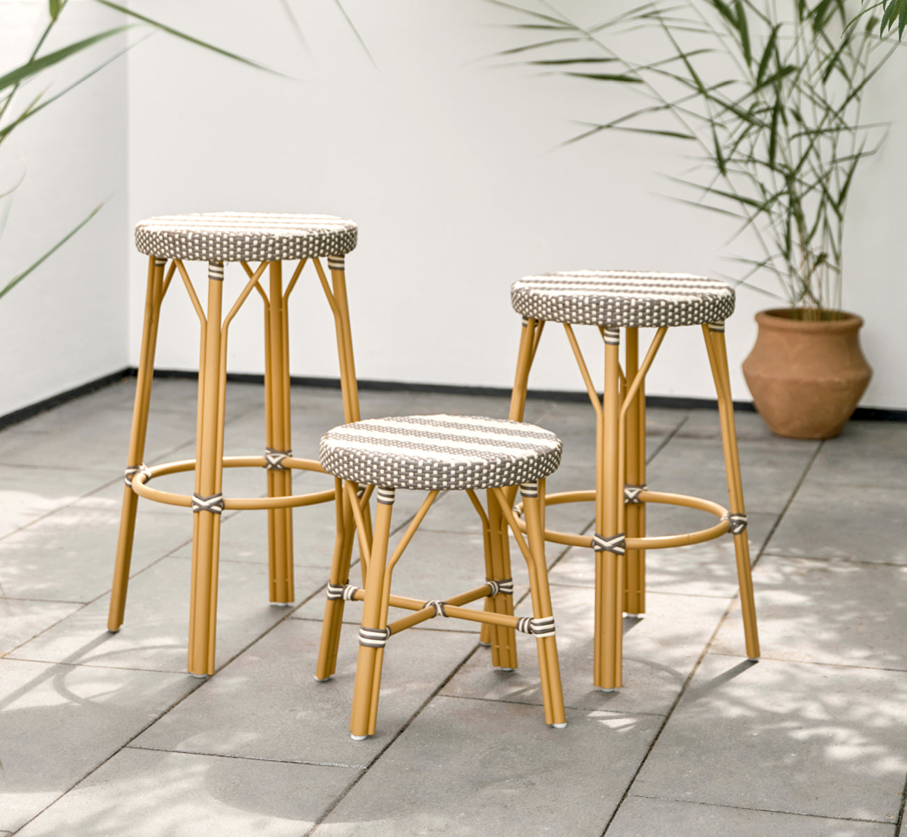 This is a lifestyle image of Simone Exterior Counter Stool in almond aluminium frame striped cappuccino ivory artfibre.