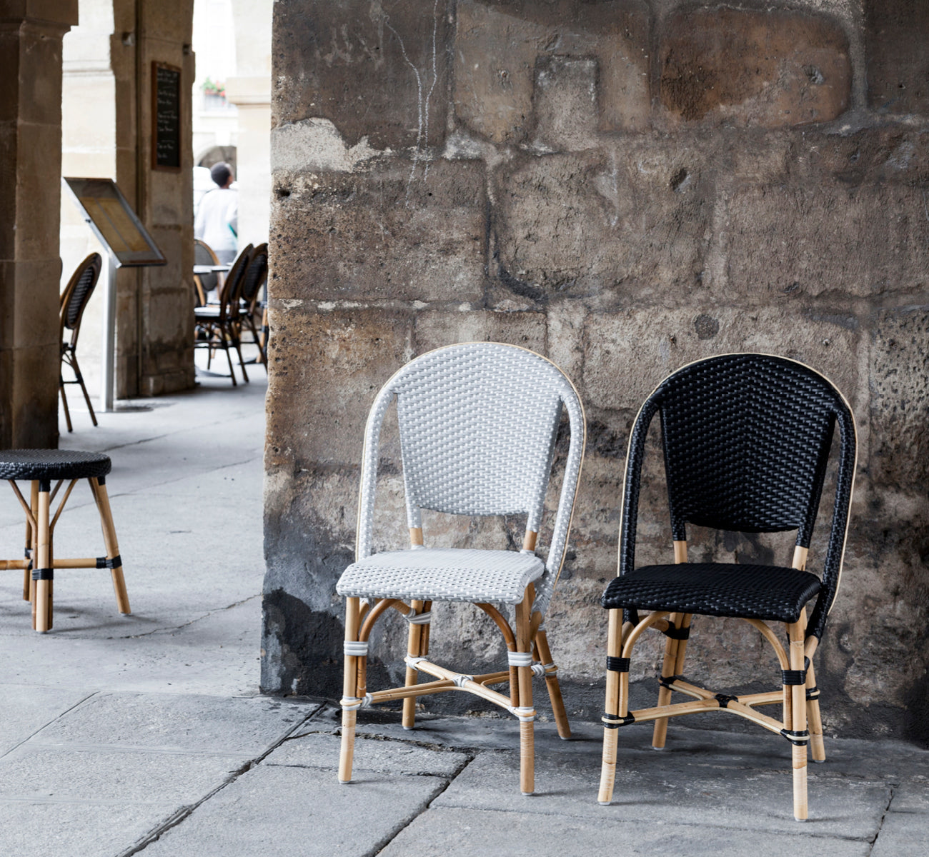 This is a lifestyle image of Sofie Dining Chair in black artfibre skin on rattan frame. Styled in a bright interior setting.