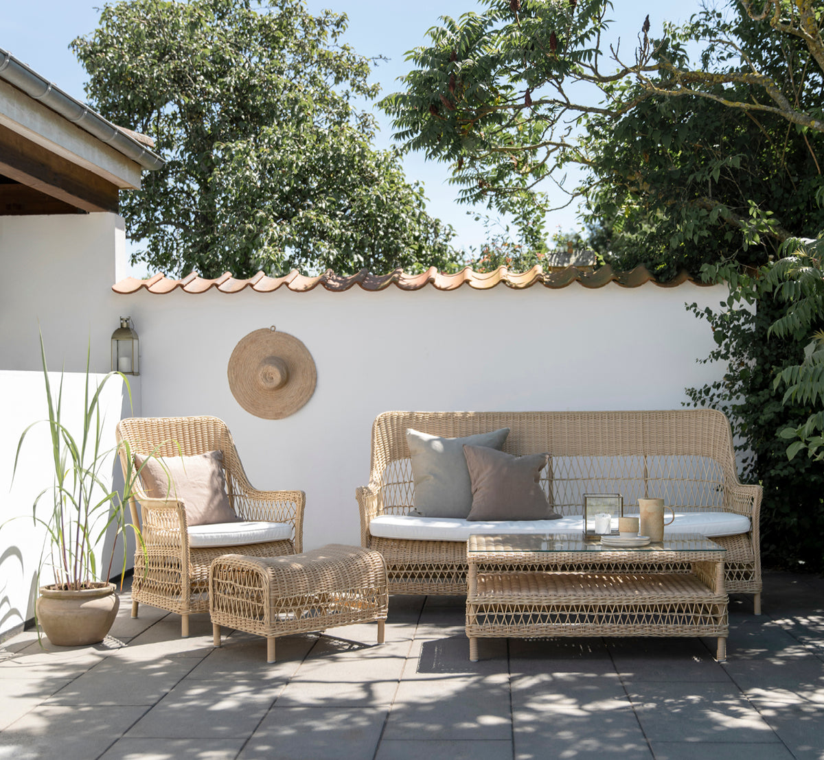 This is a lifestyle image of Dawn Sofa in natural ArtFibre Aluminium, on a coastal terrace with white wooden decking and sea views.