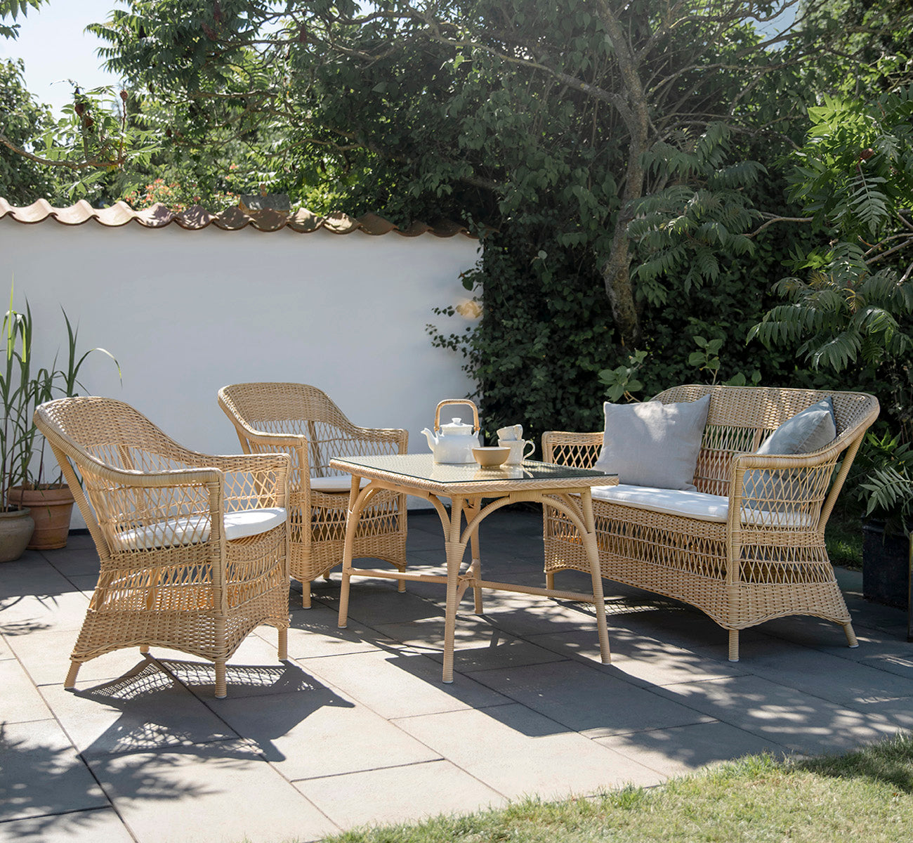 This is a lifestyle image of Victoria Exterior Coffee Table 100x60 cm in natural artfibre aluminium. Styled in a bright interior setting.
