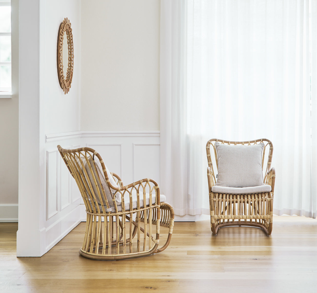 This is a lifestyle image of Tulip Lounge Chair in polished natural rattan. Paired with a matching sofa in a bright panelled room with door.