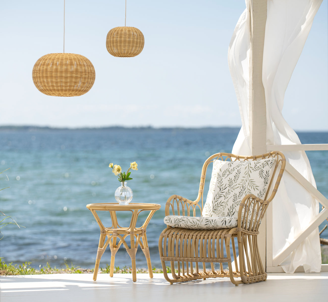 This is a lifestyle image of Tulip Exterior Lounge Chair in natural aluminium artfibre. Styled in a bright interior setting.
