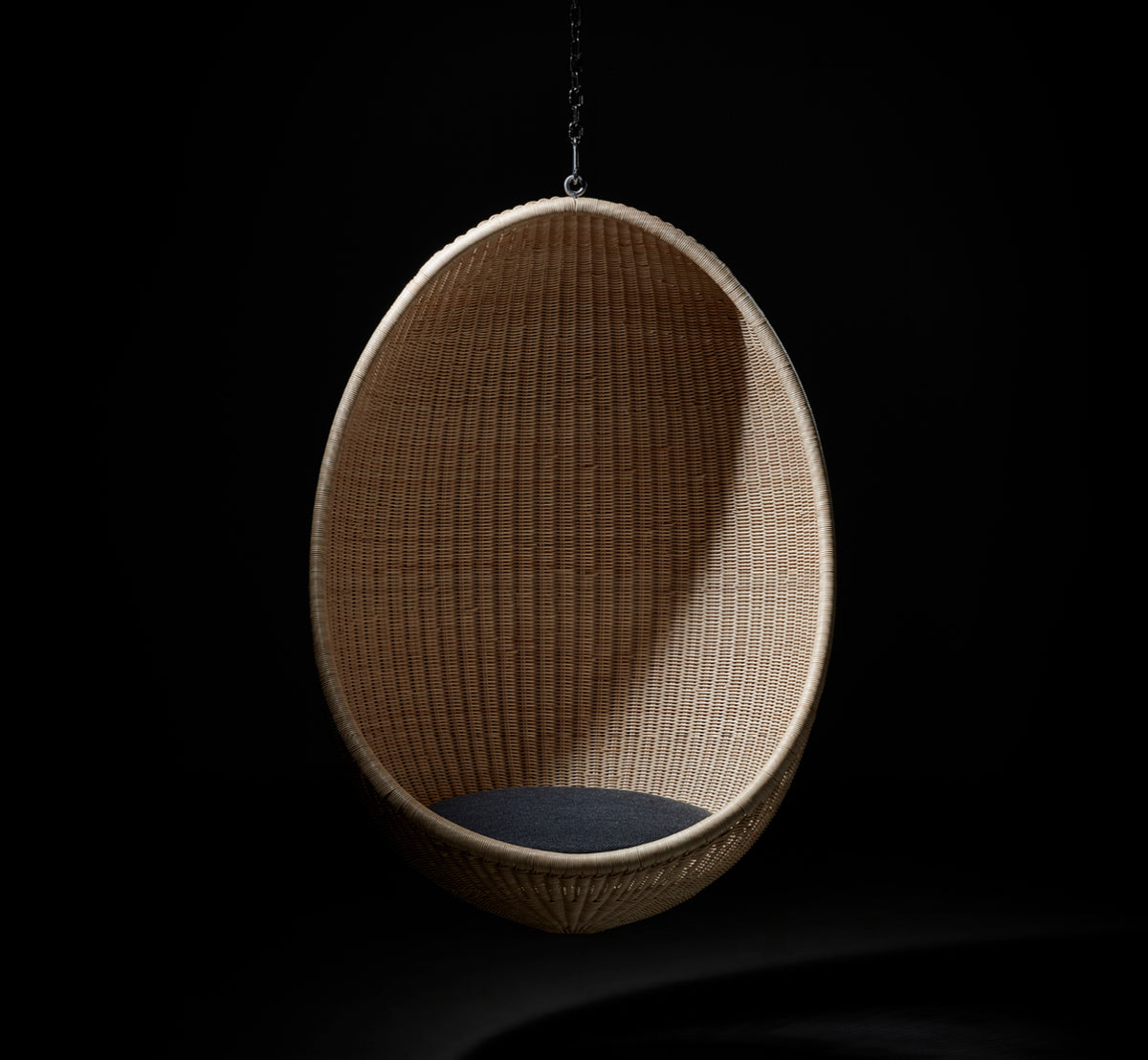 This is a lifestyle image of Hanging Egg Chair in natural core weave Rattan frame, in an elegant classical interior with ornate golden mouldings.
