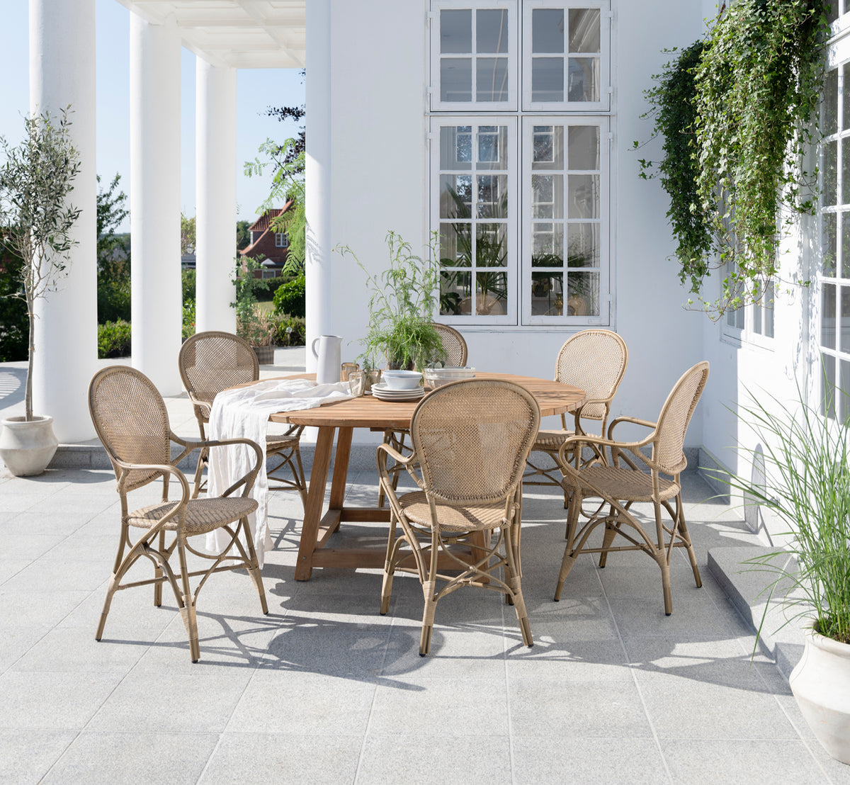This is a lifestyle image of Rossini Exterior Dining Armchair in antique aluminium artfibre. Styled in a bright interior setting.