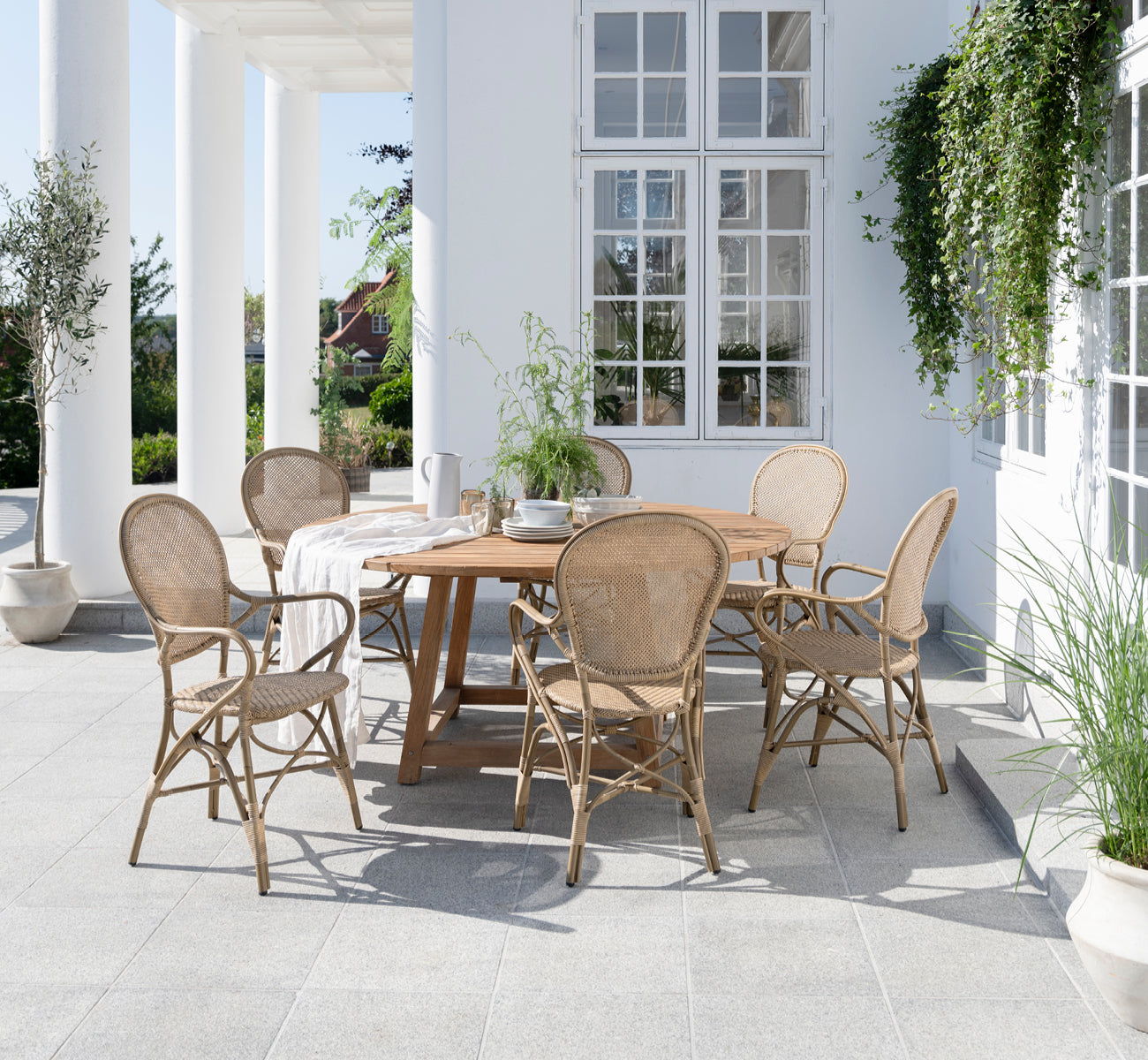 This is a lifestyle image of Rossini Exterior Dining Armchair in antique aluminium artfibre. Styled in a bright interior setting.