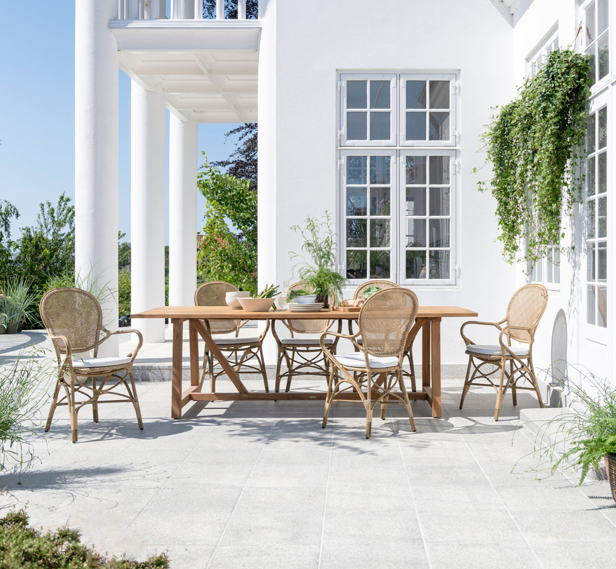 This is a lifestyle image of Rossini Exterior Dining Armchair in antique aluminium artfibre. Styled in a bright interior setting.