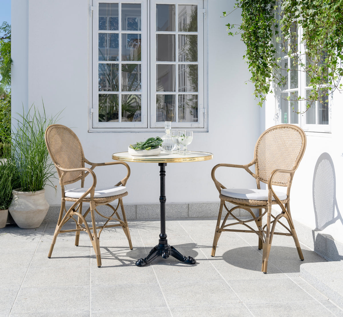 This is a lifestyle image of Rossini Exterior Dining Armchair in antique aluminium artfibre. Styled in a bright interior setting.
