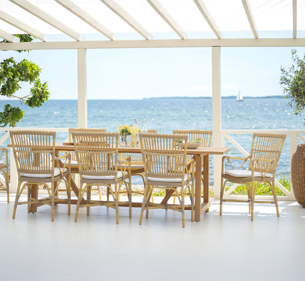 This is a lifestyle image of Piano Exterior Dining Armchair in natural aluminium artfibre. Styled in a bright interior setting.