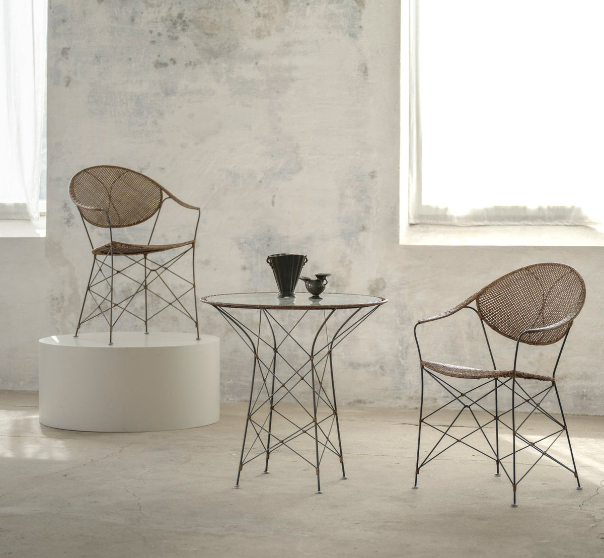 This is a lifestyle image of Funky Dining Chair in hazelnut rattan iron frame. With glass table in a pale, sunlit room.