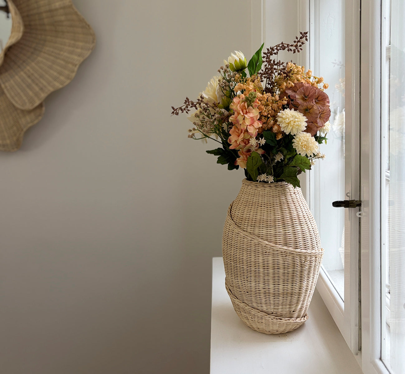This is a lifestyle image of Floris Basket in natural core weave iron frame, in a bright white interior with wainscoting, styled with dried flowers.