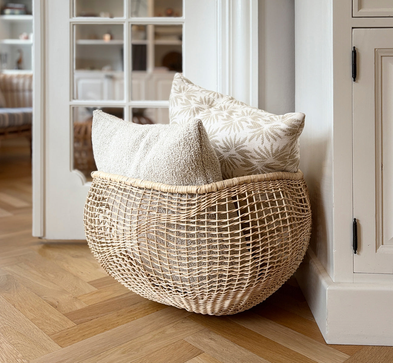 This is a lifestyle image of Folia Basket in natural core weave iron frame, in a bright white interior with wainscoting, styled with dried flowers.