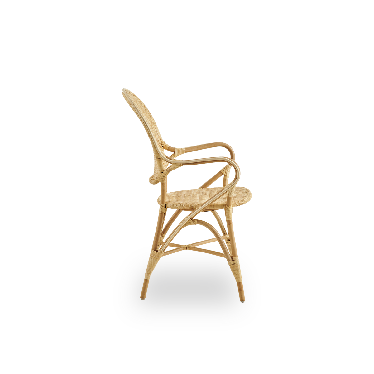 Plain side view of Rossini dining armchair made in natural rattan. Elegant wicker chair with round backrest and armrests in simple design. Handcrafted from high quality rattan.
