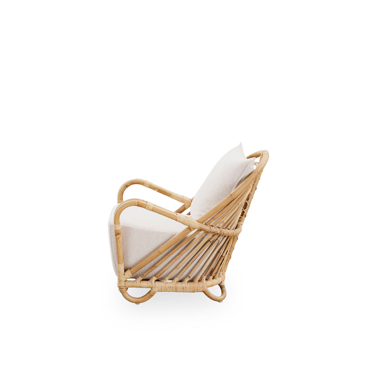 Plain side view of the Charlottenborg Lounge Chair in polished natural rattan, designed by Arne Jacobsen. The chair features a curved back and armrests integrated into the base, handcrafted from high quality Indonesian rattan.