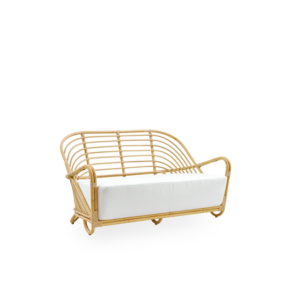 Side view of the Charlottenborg Exterior 2-seater sofa in rattan look, designed by Arne Jacobsen. The sofa features a curved back and armrests integrated into the base, handcrafted with an Alu-Rattan frame and woven ArtFibre details.