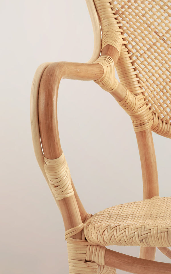 This is a close-up image of Rossini Dining Armchair in natural rattan. Detail of the light rattan armrest curve and herringbone seat.