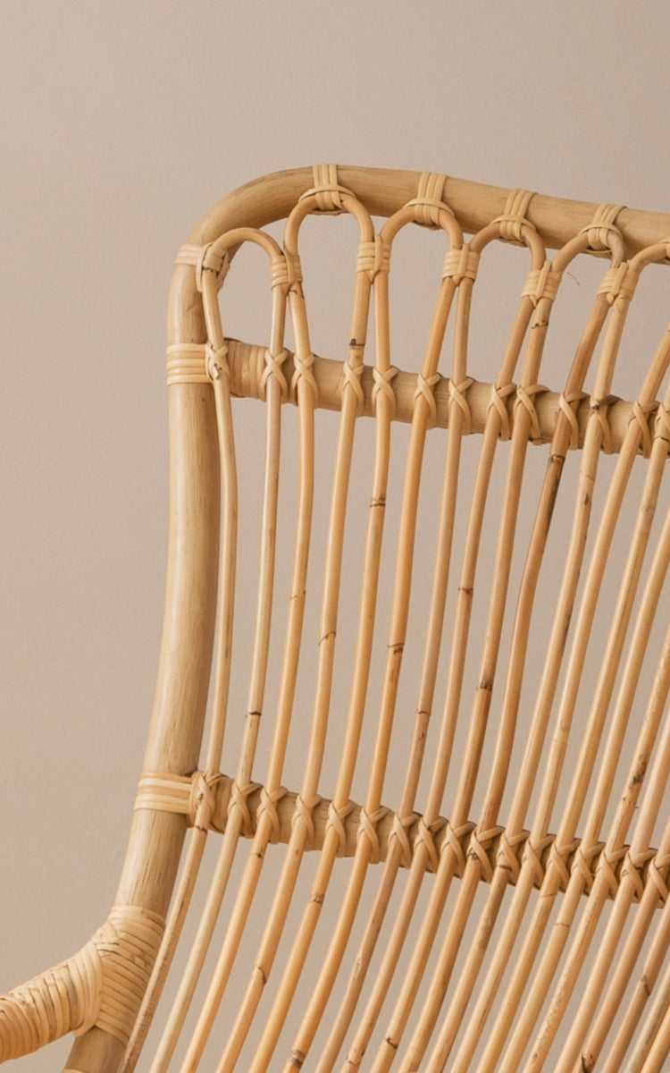 This is a close-up image of Monet Rocking Chair in natural rattan. Detail of the looped arch design and wrapped rattan binding at the top.