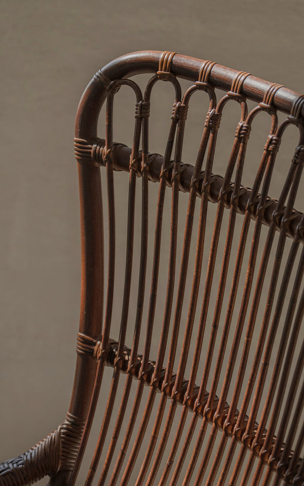 This is a close-up image of Monet Lounge Chair in brown rattan. Looped backrest and vertical rattan slats.