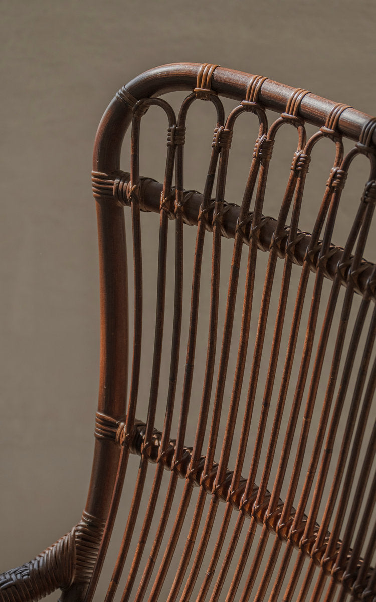 This is a close-up image of Monet Lounge Chair in brown rattan. Looped backrest and vertical rattan slats.