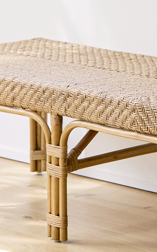 This is a close-up image of Luis Bench in antique rattan. The herringbone woven seat and handbound rattan frame joints showcase the craftsmanship.