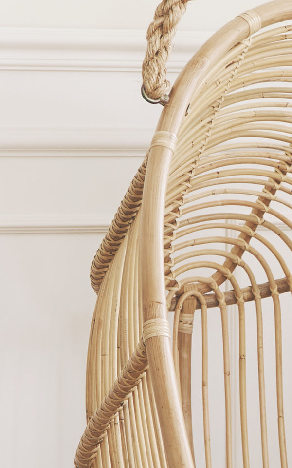 This is a close-up image of Renoir Hanging Chair in natural rattan. Detail of the natural rattan frame with radial spokes and rope hanger.