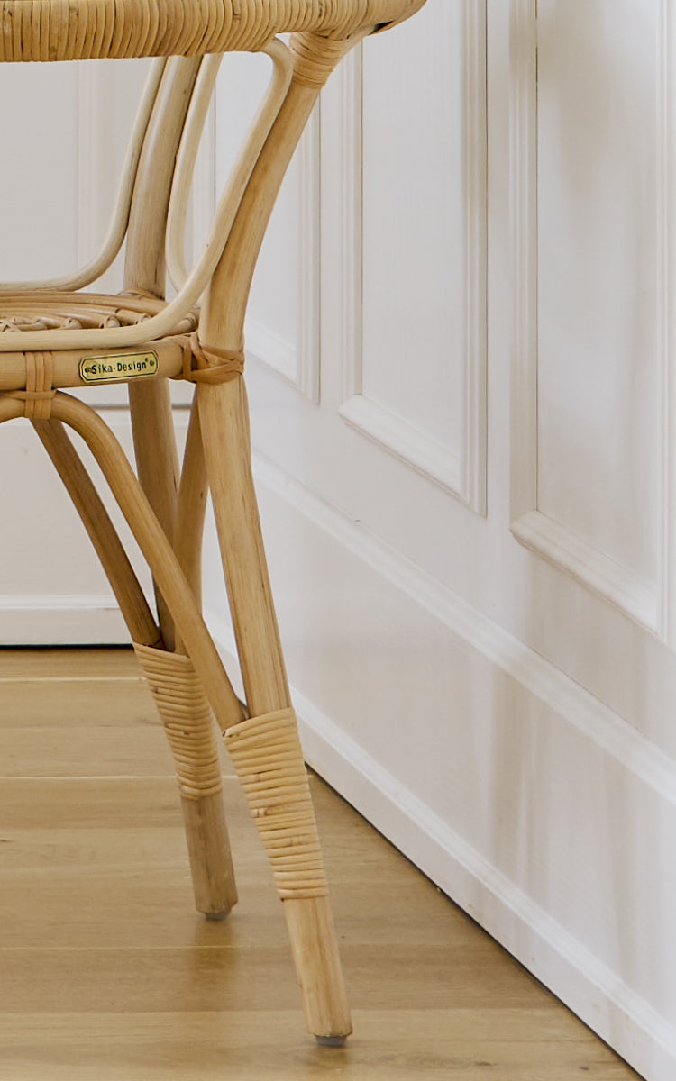 This is a close-up image of Tony Side Table in natural rattan. Detail of the glass top edge and wrapped rattan frame construction.