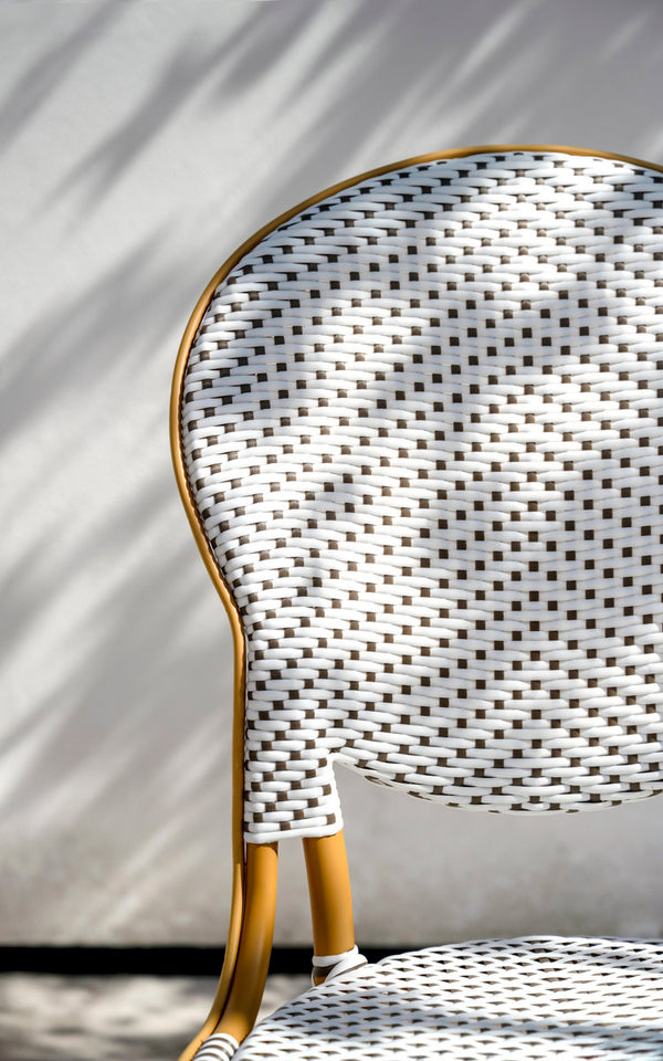This is a close-up image of Isabell Exterior Dining Chair in almond aluminium frame white w cappuccino dot artfibre. Woven oval backrest in sunlight.
