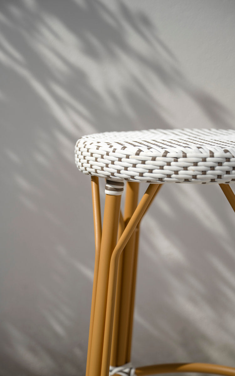 This is a close-up image of Simone Exterior Bar Stool in almond aluminium frame white w cappuccino dot artfibre. Woven seat by a white wall.