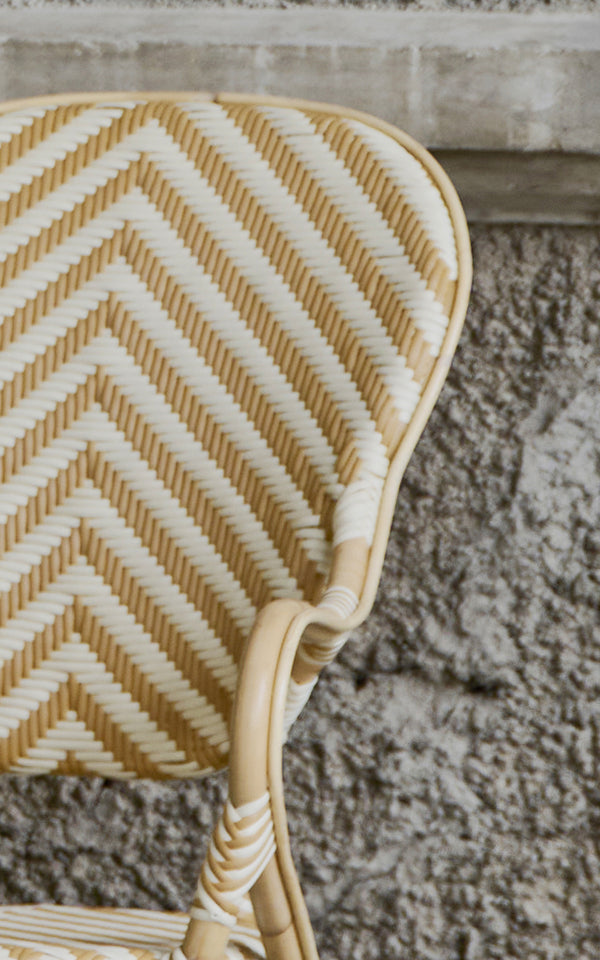 This is a close-up image of Isabell Dining Armchair in chevron Honey Ivory ArtFibre Skin on Rattan frame.