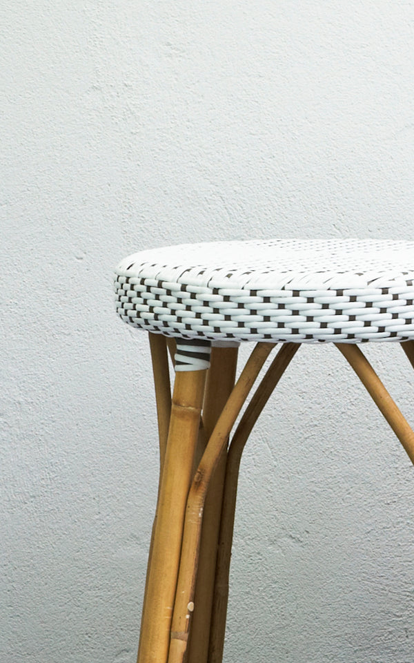 This is a close-up image of Simone Counter Stool in white w cappuccino dot ArtFibre Skin on Rattan frame. Shown against a white plaster wall.