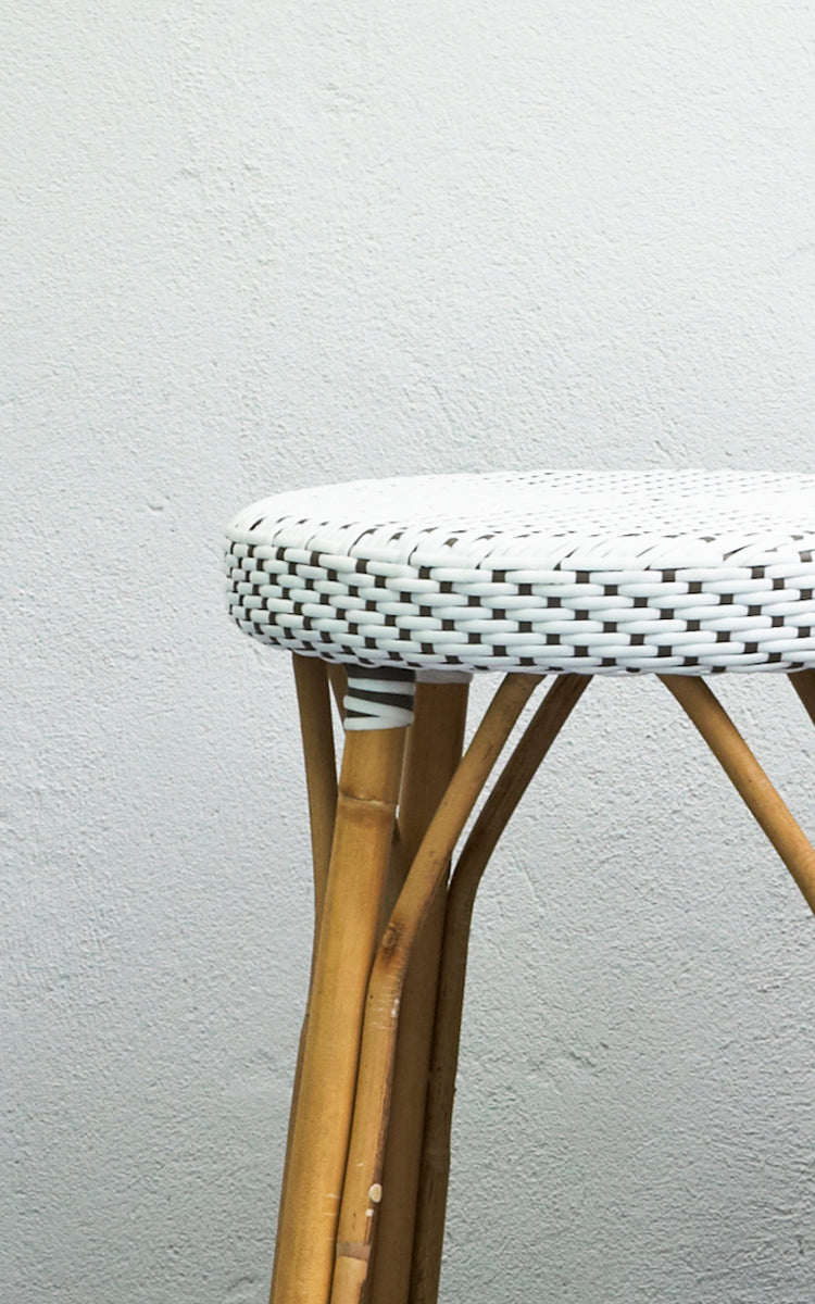 This is a close-up image of Simone Counter Stool in white w cappuccino dot ArtFibre Skin on Rattan frame. Shown against a white plaster wall.