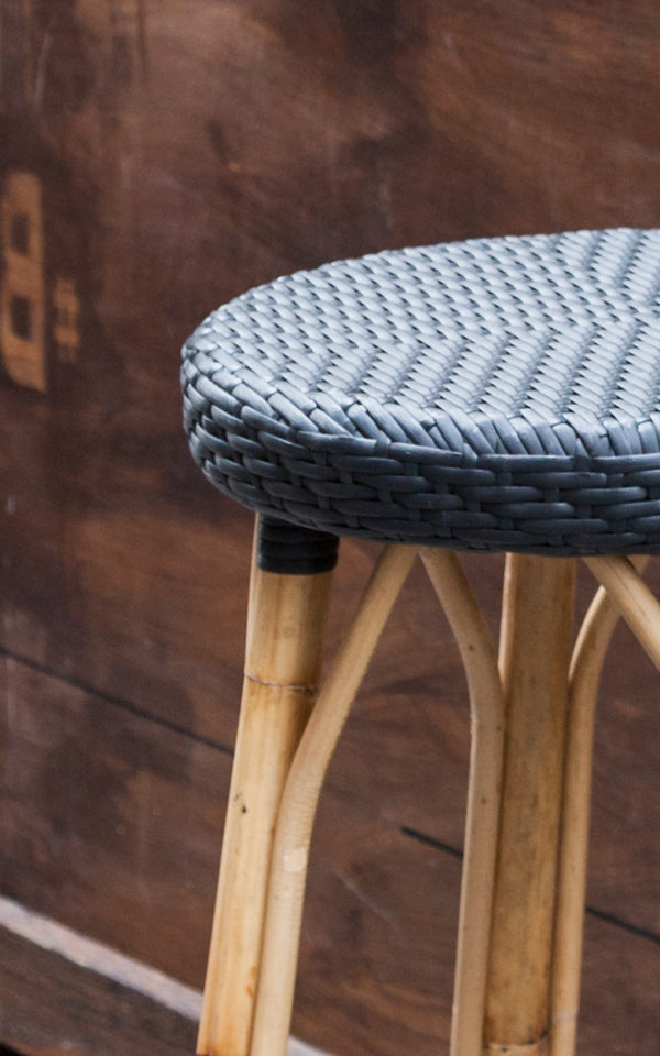 This is a close-up image of Simone Bar Stool in black ArtFibre Skin on Rattan frame. Detail of the woven seat against dark wood.