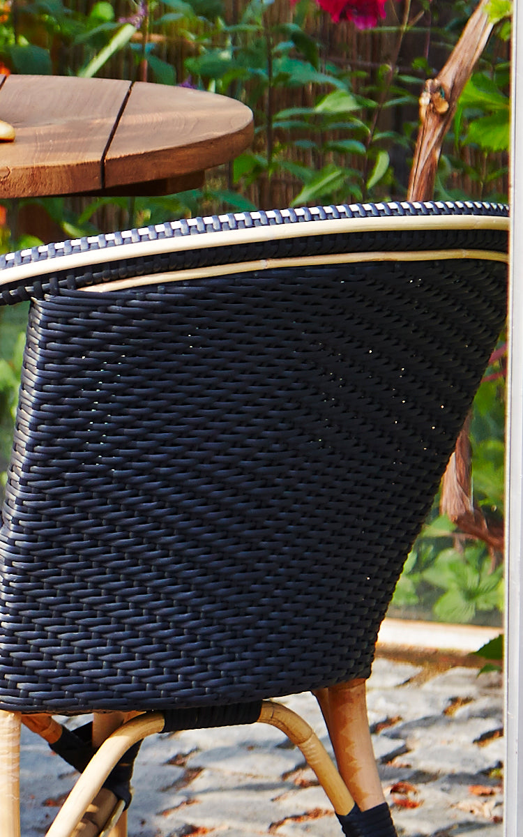 This is a close-up image of Madeleine Dining Chair in black ArtFibre skin on rattan frame. Dense black weave with rattan frame edge.