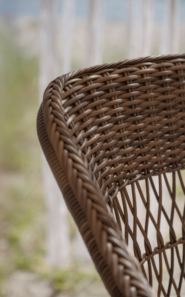 This is a close-up image of Charlot Exterior Chair in brown artfibre aluminum. Braided edge and open weave backrest.