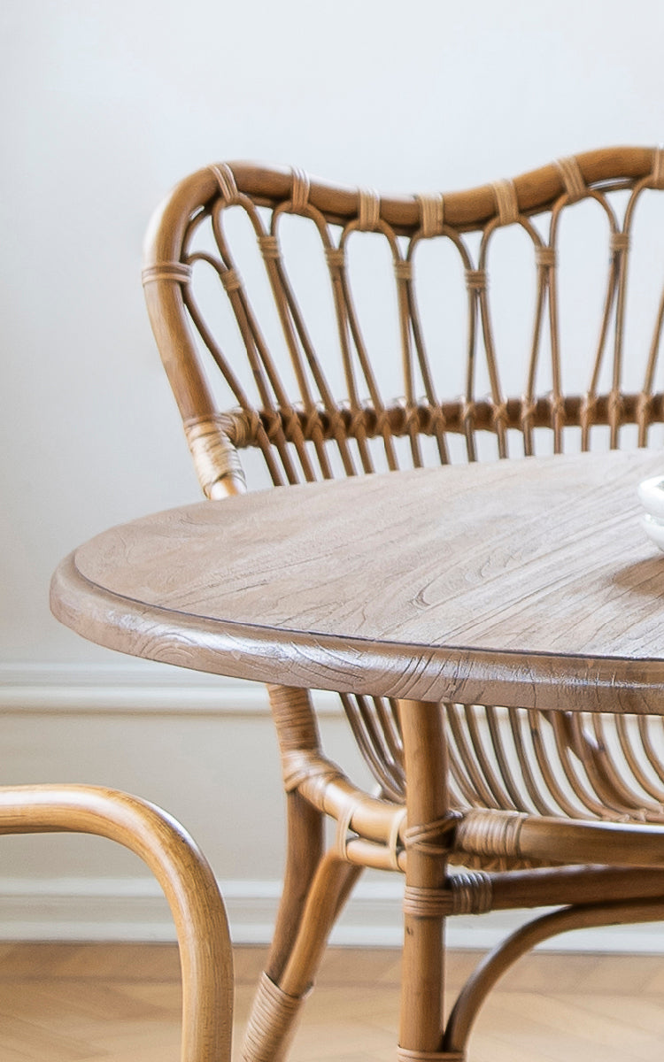 This is a close-up image of Michel Teak Dining Table in teak indoor. Detail of the round teak tabletop edge and pedestal base.