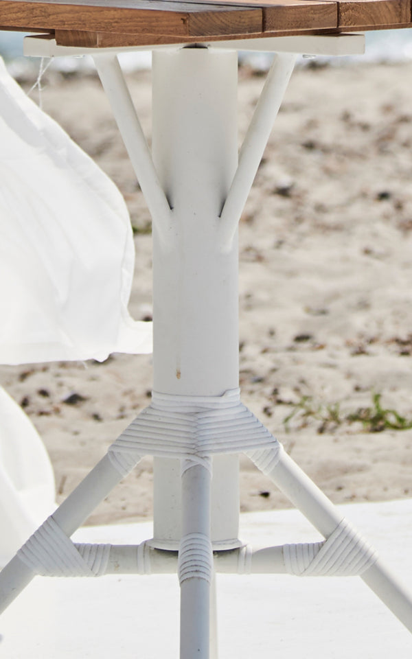 This is a close-up image of Nicole Cáfe Table Teak 70x70 cm in white aluminium frame white artfibre.