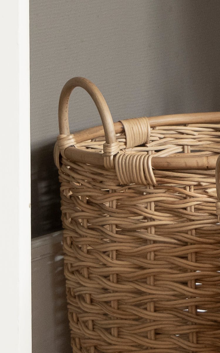 This is a close-up image of Sarah Basket set in natural rattan. Detail of the braided rattan handle and chunky woven basket body.